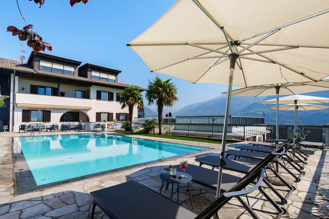 Outdoor swimming pool with lounge chairs and umbrellas at a villa with mountain views