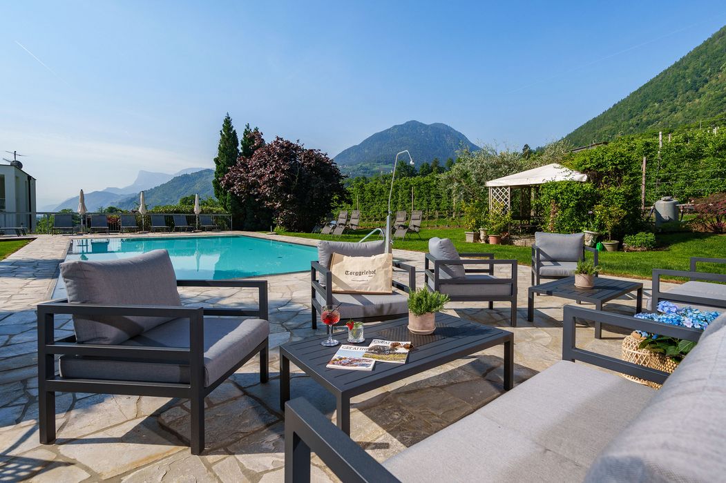 Modernes Gartenmöbel-Set mit Pool und Berglandschaft im Hintergrund an sonnigem Tag